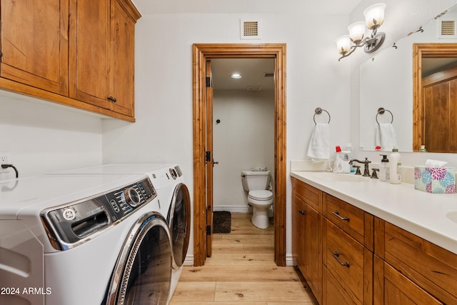 washroom with washer and clothes dryer, light wood finished floors, visible vents, a sink, and laundry area