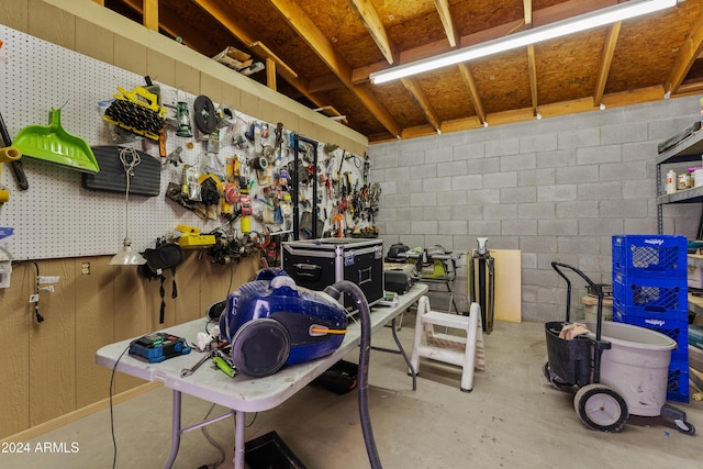 miscellaneous room with concrete block wall, concrete floors, and a workshop area