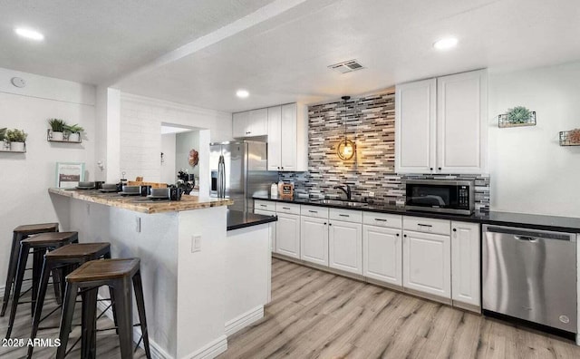 3330 E Cypress St, Phoenix, AZ 85008 - kitchen featuring appliances with stainless steel finishes, a sink, a breakfast bar, white cabinetry, and light wood finished floors