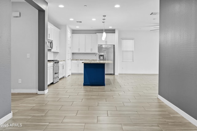 kitchen featuring hanging light fixtures, an island with sink, appliances with stainless steel finishes, and white cabinetry