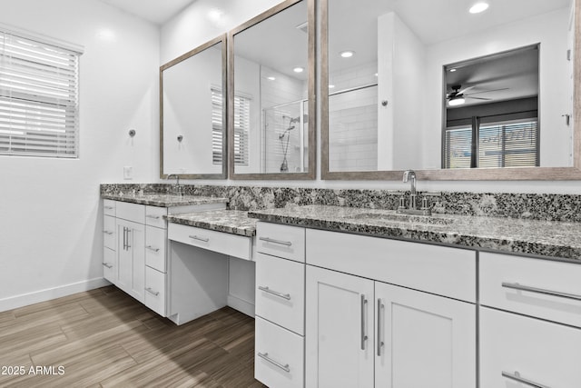 bathroom with a shower with shower door, vanity, plenty of natural light, ceiling fan, and hardwood / wood-style floors