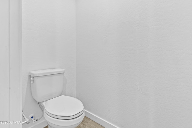 bathroom with toilet and hardwood / wood-style floors