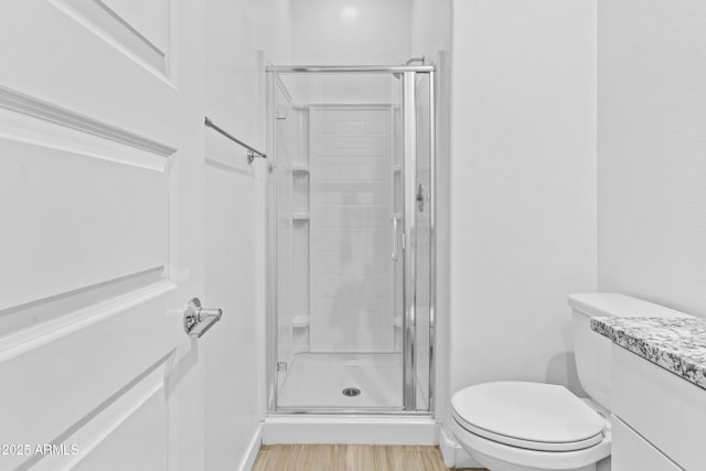 bathroom featuring vanity, hardwood / wood-style flooring, toilet, and walk in shower