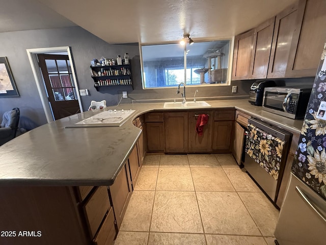 kitchen featuring light tile patterned floors, kitchen peninsula, stove, white stovetop, and sink