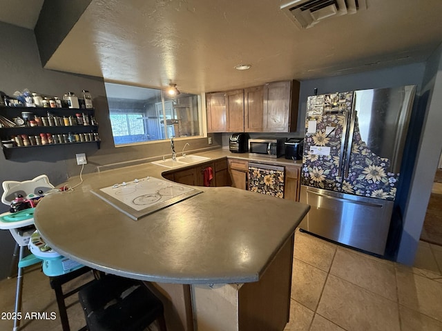 kitchen featuring kitchen peninsula, sink, light tile patterned flooring, appliances with stainless steel finishes, and a kitchen breakfast bar