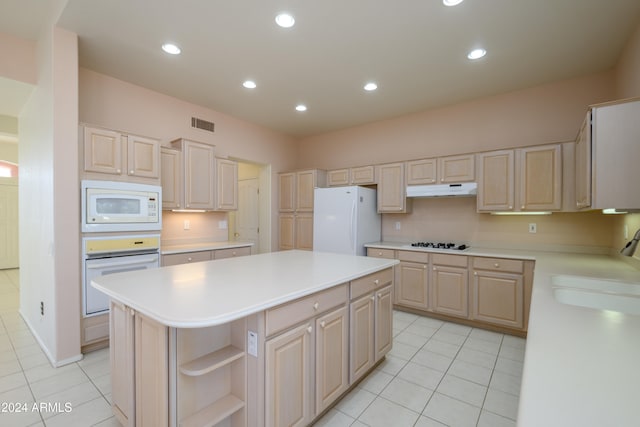 kitchen featuring light tile patterned floors, white appliances, a center island, and light brown cabinets