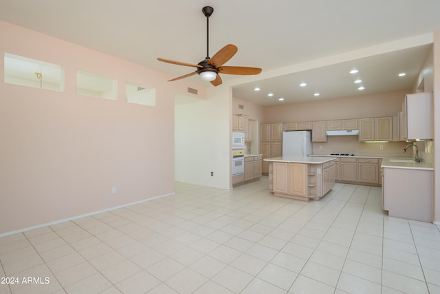 kitchen featuring light tile patterned flooring, white appliances, sink, light brown cabinetry, and a kitchen island