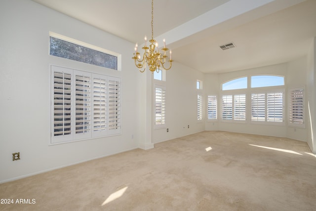 carpeted spare room featuring an inviting chandelier