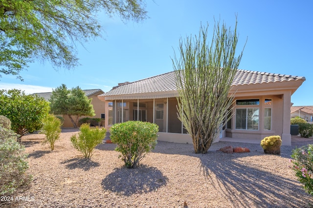 back of property with central AC and a sunroom