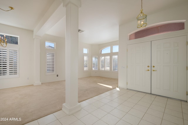 carpeted foyer entrance with a notable chandelier and decorative columns