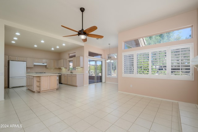 kitchen with light brown cabinets, a center island, white fridge, and plenty of natural light