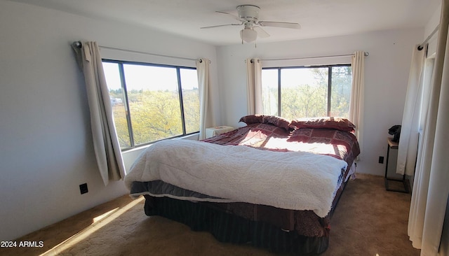 carpeted bedroom featuring multiple windows and ceiling fan