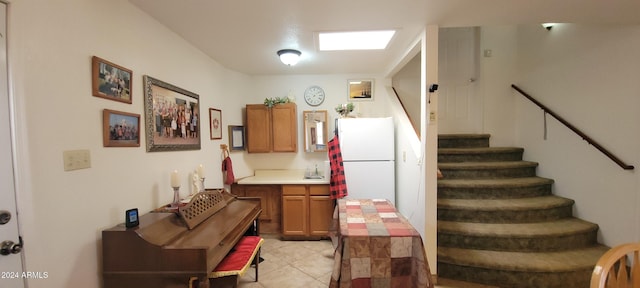 kitchen featuring white refrigerator, light tile patterned floors, and sink