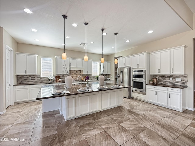 14572 W Medlock Dr, Litchfield Park, AZ 85340 - kitchen featuring dark countertops, stainless steel appliances, healthy amount of natural light, decorative backsplash, and recessed lighting