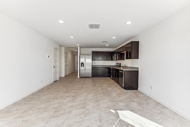 kitchen with light tile patterned flooring, sink, light stone counters, dark brown cabinets, and appliances with stainless steel finishes