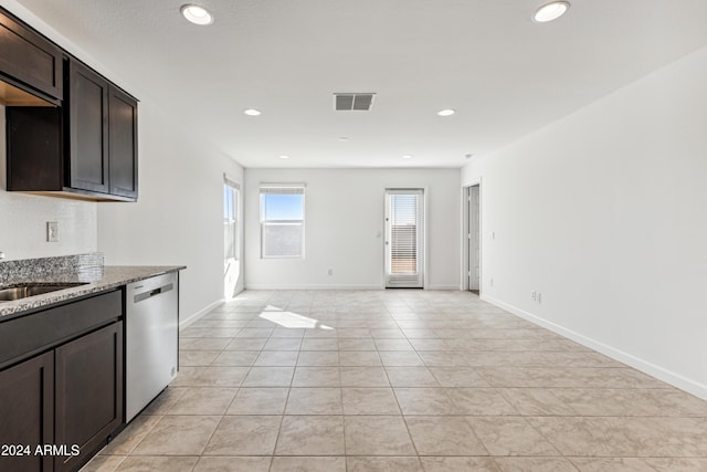 kitchen with sink, light stone counters, dark brown cabinets, light tile patterned floors, and stainless steel dishwasher