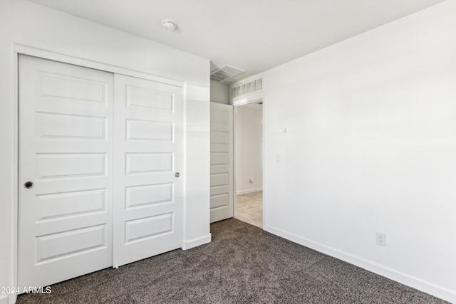 unfurnished bedroom with dark carpet and a closet