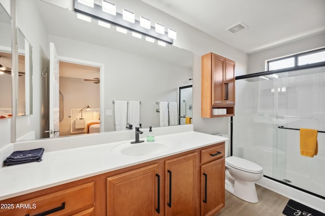 bathroom featuring vanity, a shower with shower door, hardwood / wood-style floors, and toilet