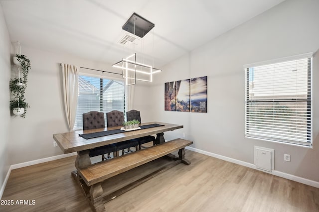 dining space with lofted ceiling and light hardwood / wood-style flooring