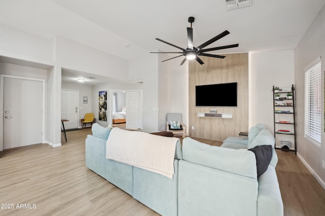 living room with ceiling fan, lofted ceiling, and light wood-type flooring