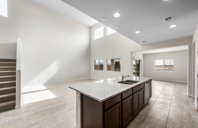 17857 W Getty Dr, Goodyear, AZ 85338 - kitchen featuring a center island with sink, dishwasher, light stone counters, dark brown cabinetry, and sink