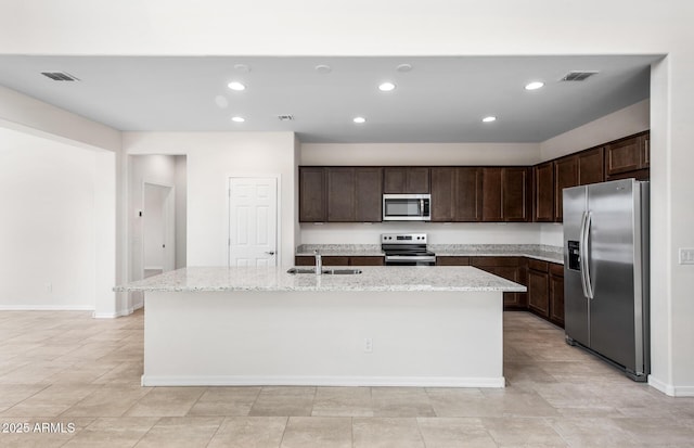 17857 W Getty Dr, Goodyear, AZ 85338 - kitchen with appliances with stainless steel finishes, dark brown cabinets, an island with sink, light stone counters, and sink
