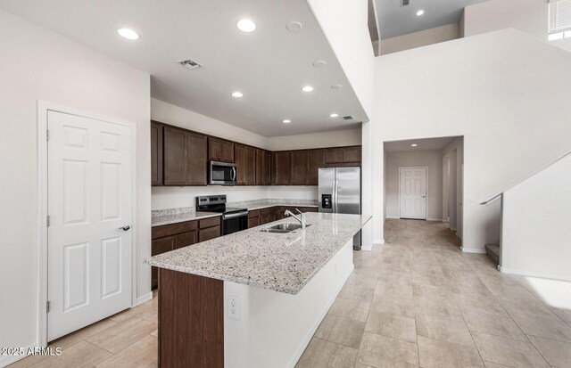17857 W Getty Dr, Goodyear, AZ 85338 - kitchen featuring a center island with sink, sink, dark brown cabinets, light stone counters, and appliances with stainless steel finishes