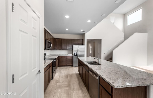 17857 W Getty Dr, Goodyear, AZ 85338 - kitchen featuring an island with sink, light stone countertops, sink, dark brown cabinets, and appliances with stainless steel finishes