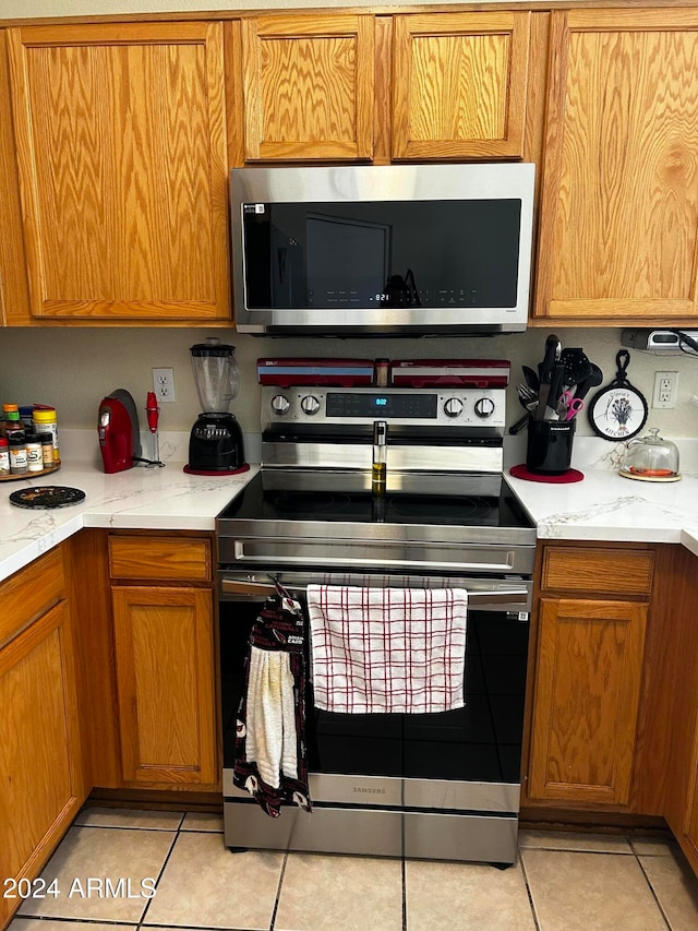 kitchen featuring light stone countertops, light tile patterned floors, and stainless steel appliances