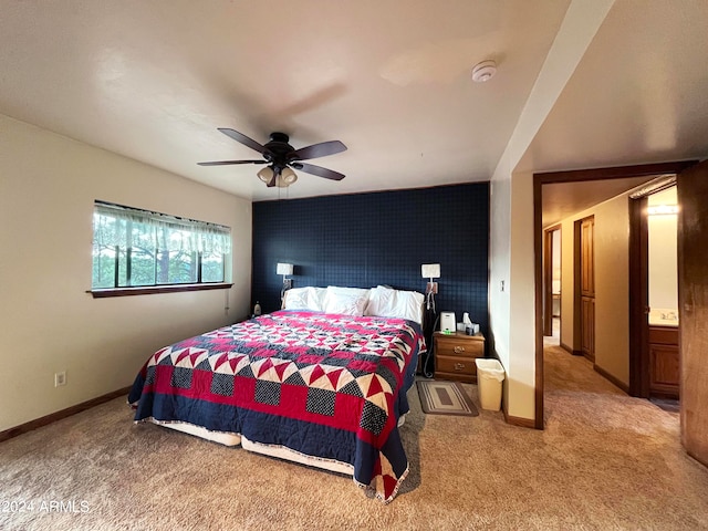 carpeted bedroom with ensuite bath and ceiling fan