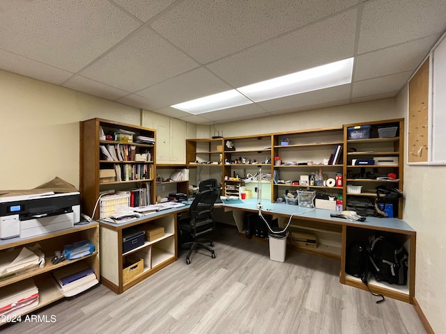 home office with built in desk, a drop ceiling, and light hardwood / wood-style flooring