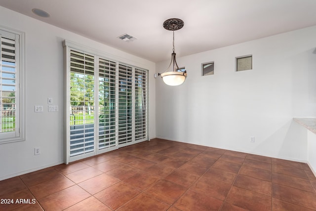 unfurnished room with dark tile patterned floors, visible vents, and a wealth of natural light