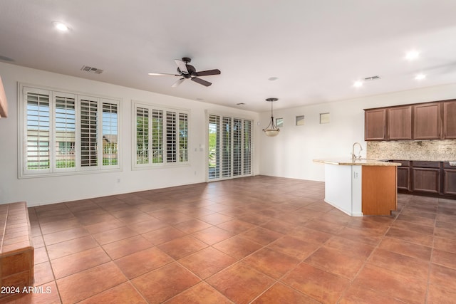 kitchen featuring visible vents, open floor plan, decorative backsplash, light stone countertops, and pendant lighting