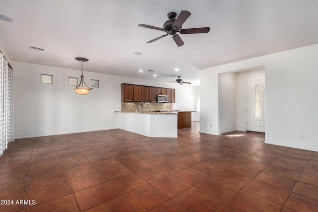 unfurnished living room featuring ceiling fan, dark tile patterned floors, and visible vents