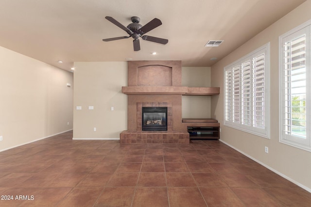 unfurnished living room featuring ceiling fan, a tiled fireplace, and tile patterned floors