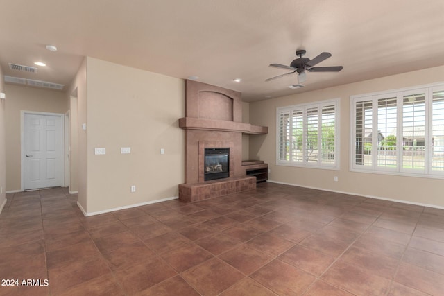 unfurnished living room with ceiling fan, dark tile patterned floors, and a fireplace