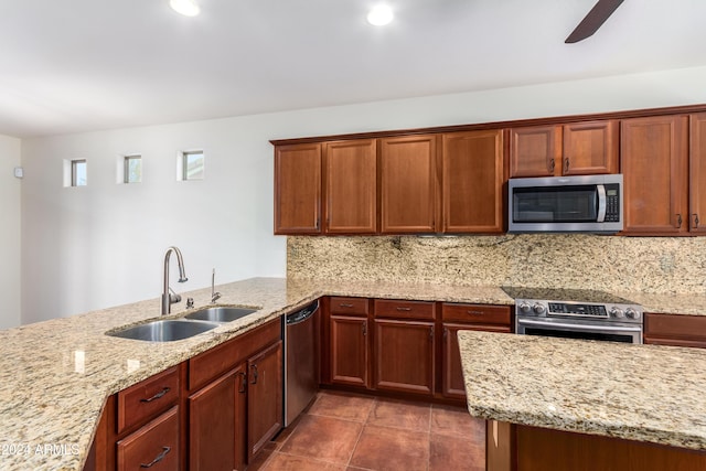 kitchen with light stone countertops, backsplash, stainless steel appliances, and a sink