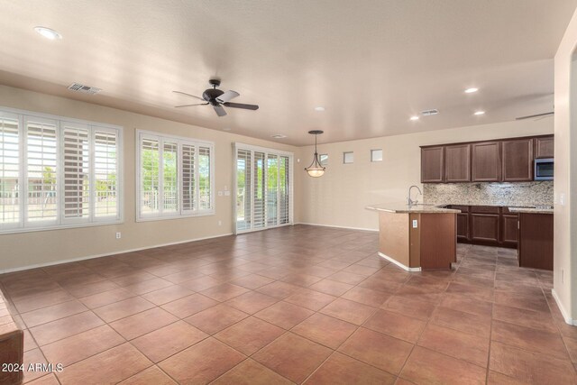 kitchen with decorative backsplash, tile patterned flooring, sink, pendant lighting, and ceiling fan