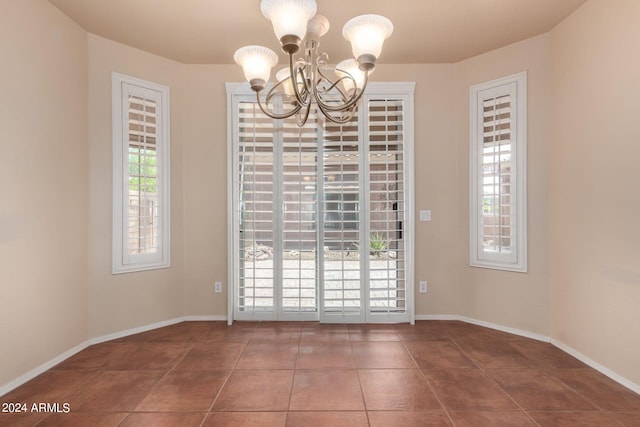 unfurnished dining area featuring tile patterned floors and an inviting chandelier