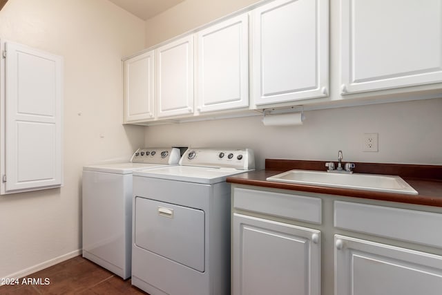 clothes washing area featuring cabinet space, a sink, washer and clothes dryer, and baseboards