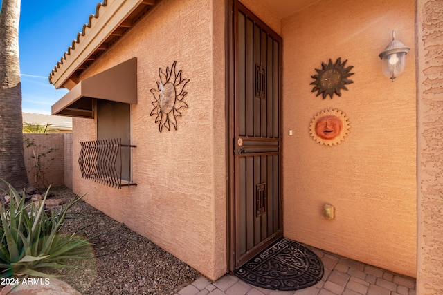 doorway to property with fence and stucco siding