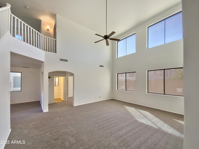 1274 W Dexter Way, San Tan Valley, AZ 85143 - unfurnished living room with carpet flooring, visible vents, ceiling fan, arched walkways, and a high ceiling