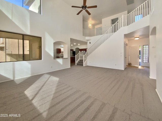 1274 W Dexter Way, San Tan Valley, AZ 85143 - unfurnished living room with arched walkways, carpet flooring, stairway, a ceiling fan, and a high ceiling