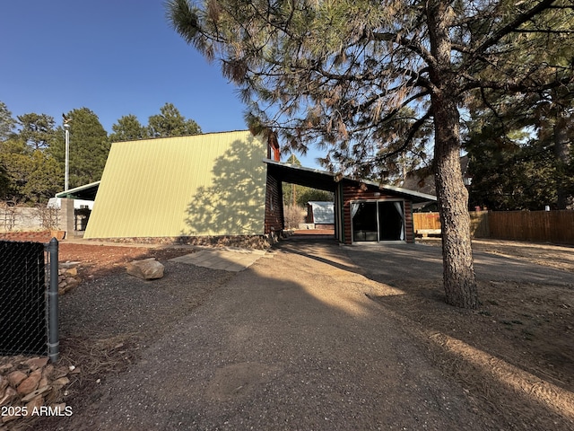 view of side of home featuring an outdoor structure, an outbuilding, driveway, and fence