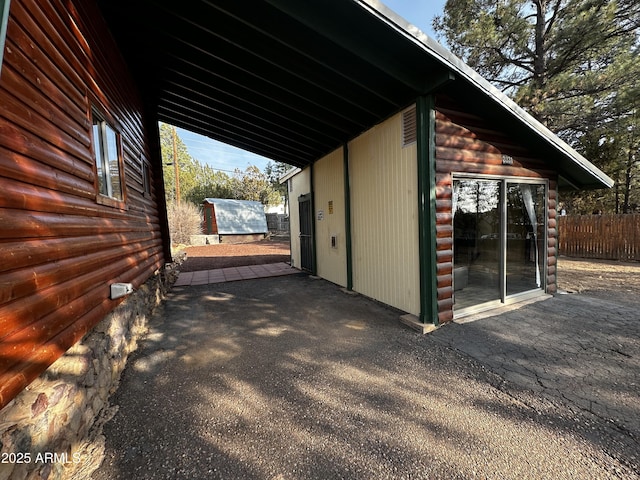 view of side of property featuring an outbuilding, a shed, fence, and a patio