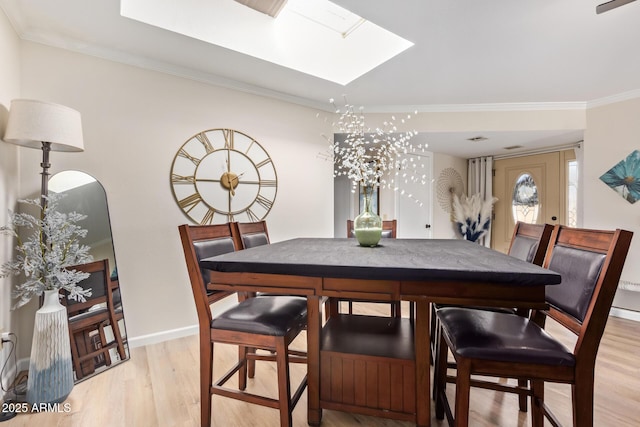 dining space with baseboards, a skylight, light wood-style flooring, and crown molding