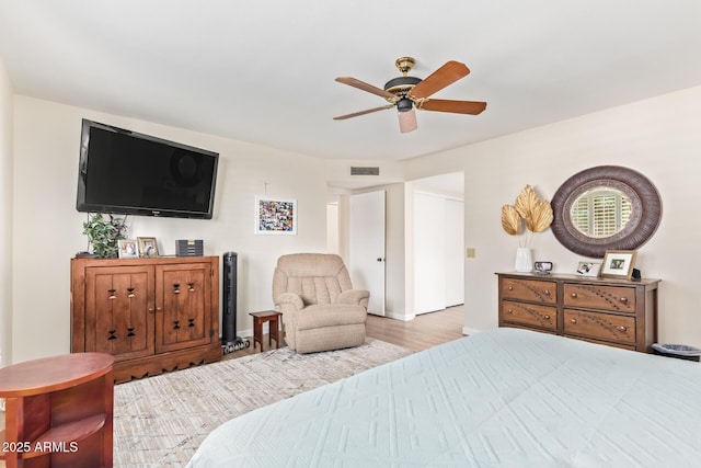 bedroom featuring light wood finished floors, visible vents, and a ceiling fan