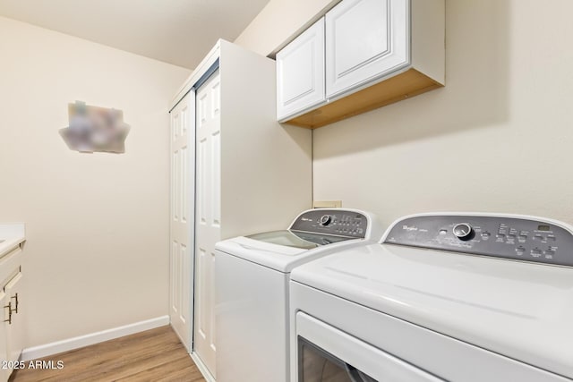 laundry room featuring cabinet space, baseboards, light wood-style floors, and independent washer and dryer