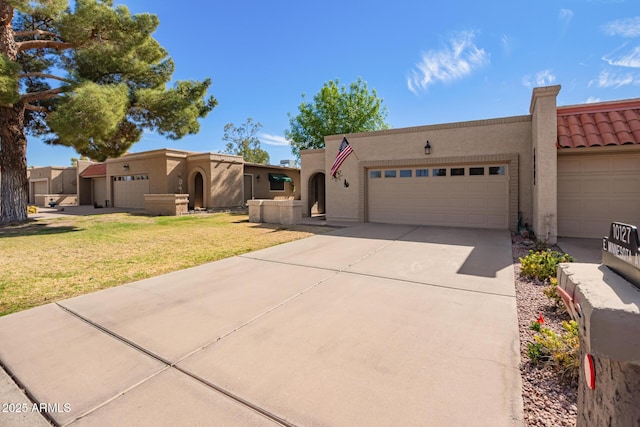 adobe home with driveway, a front lawn, an attached garage, and stucco siding