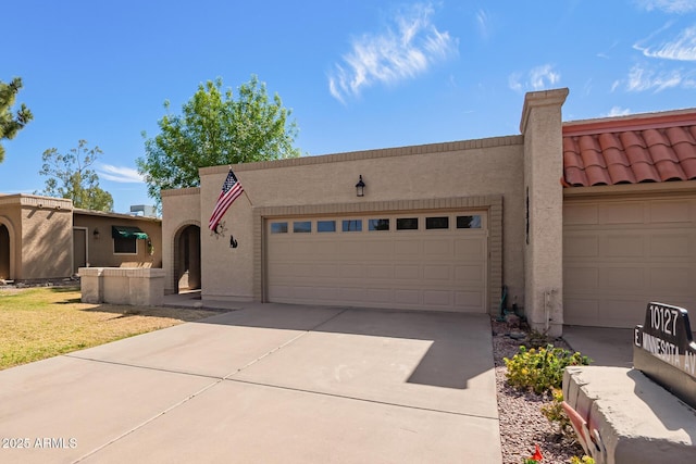 southwest-style home with a tiled roof, an attached garage, driveway, and stucco siding